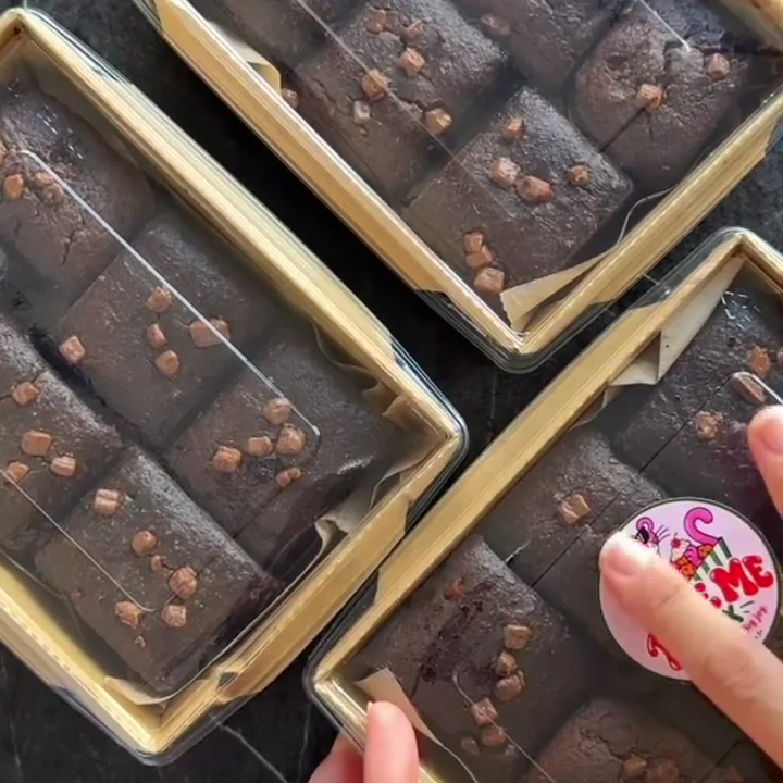Şeffaf kapaklı kraft kutularda brownieler, üstüne Bite Me Box etiketi yapıştırılıyor